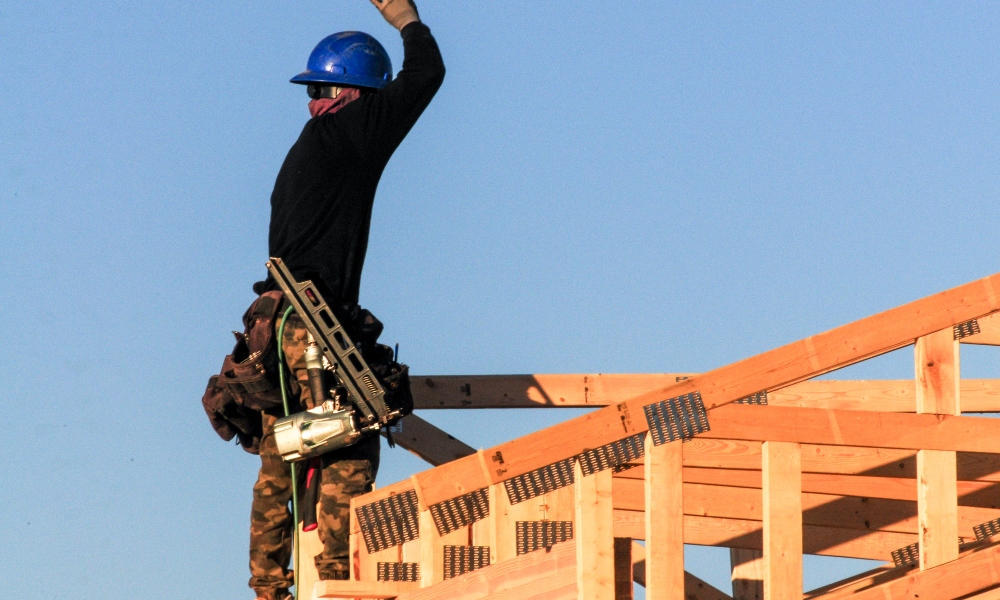 Man standing atop house meant to represent residential construction data and housing starts for February